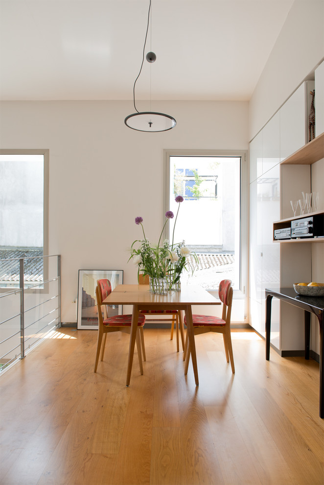 Exemple d'une salle à manger ouverte sur le salon tendance de taille moyenne avec un mur blanc et un sol en bois brun.