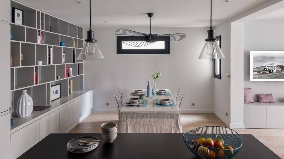 Cette image montre une salle à manger ouverte sur le salon design de taille moyenne avec un mur gris et parquet clair.