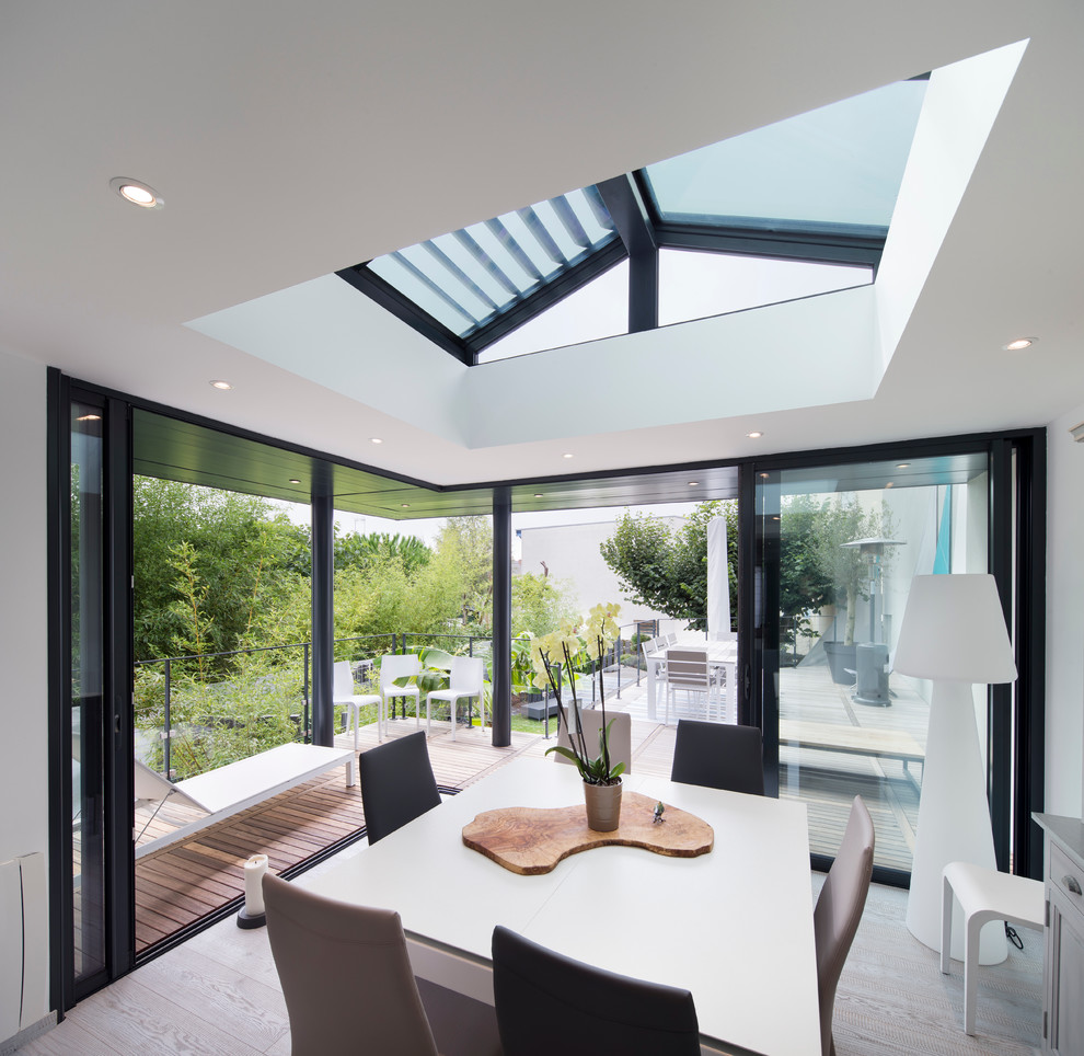 Idées déco pour une salle à manger contemporaine fermée et de taille moyenne avec parquet clair, un mur blanc et éclairage.