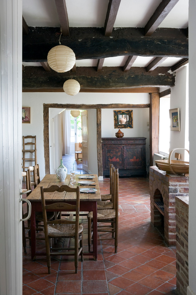 Cette photo montre une salle à manger nature fermée et de taille moyenne avec un mur blanc et tomettes au sol.