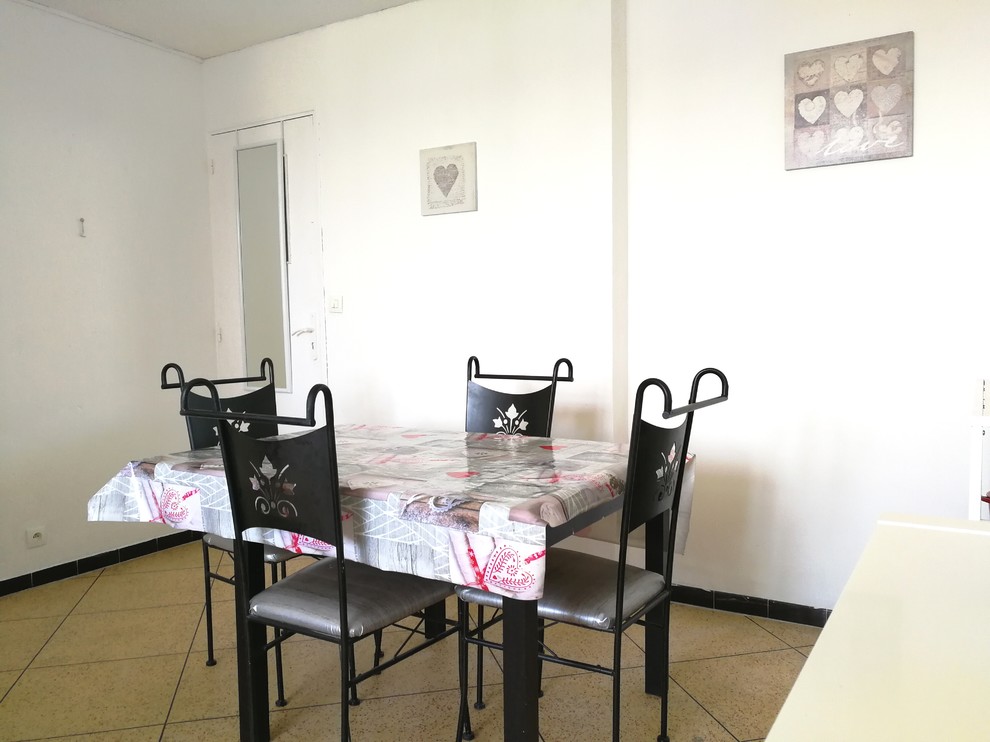 Foto di una sala da pranzo aperta verso il soggiorno tradizionale di medie dimensioni con pareti bianche, pavimento in terracotta, nessun camino e pavimento beige