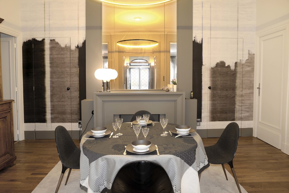 Idée de décoration pour une salle à manger tradition fermée et de taille moyenne avec un mur blanc, un sol en bois brun et une cheminée standard.