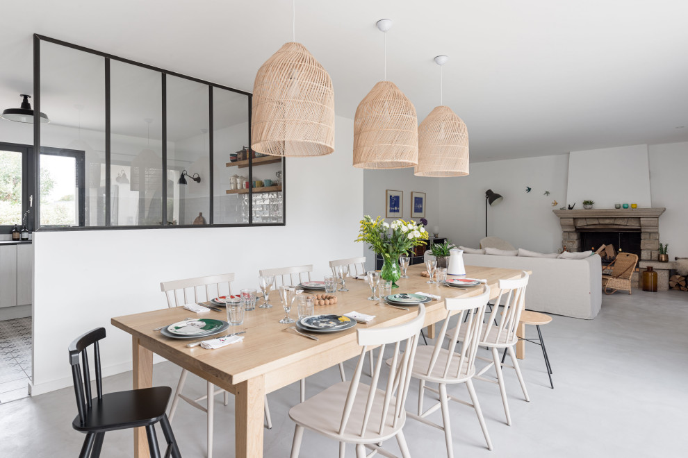 Réalisation d'une salle à manger ouverte sur la cuisine nordique de taille moyenne avec un mur blanc, une cheminée standard, un manteau de cheminée en pierre et un sol gris.