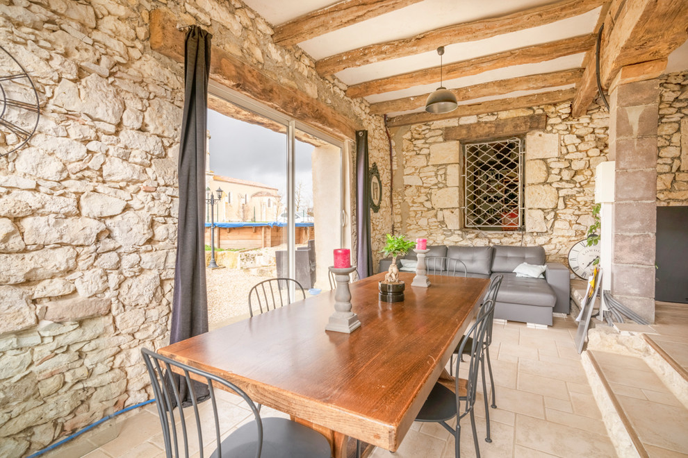 На фото: гостиная-столовая в средиземноморском стиле с бежевыми стенами и бежевым полом без камина с