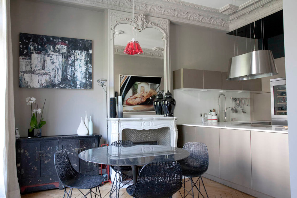 Aménagement d'une salle à manger ouverte sur le salon éclectique de taille moyenne avec un mur gris, parquet clair, une cheminée standard et un manteau de cheminée en pierre.