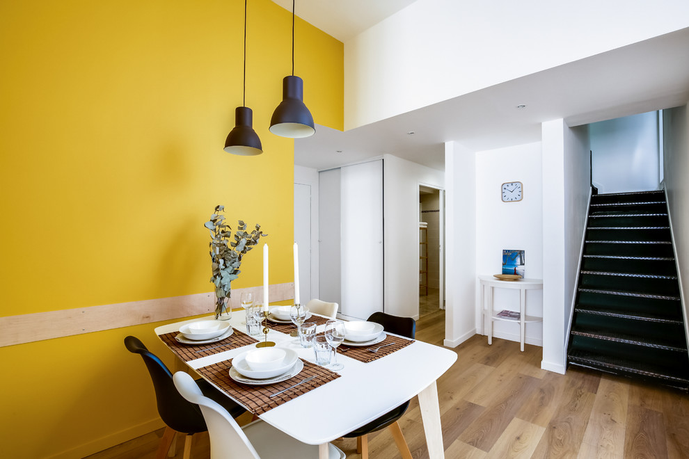 Large scandinavian dining room in Montpellier with yellow walls and vinyl flooring.