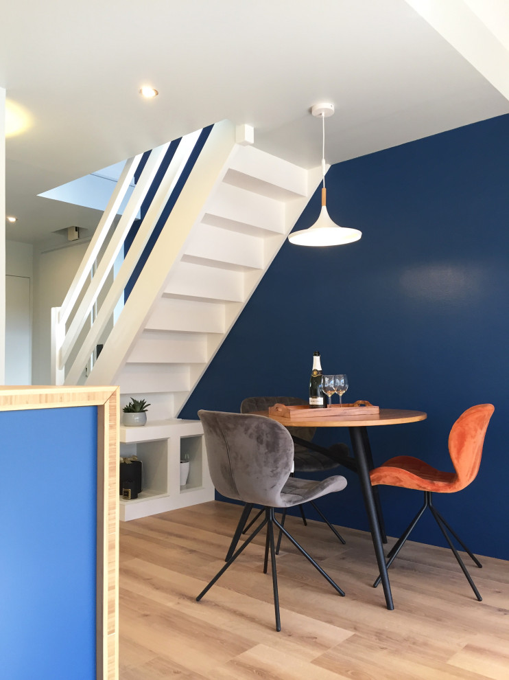 Réalisation d'une petite salle à manger ouverte sur le salon design avec un mur bleu, parquet clair et un sol beige.