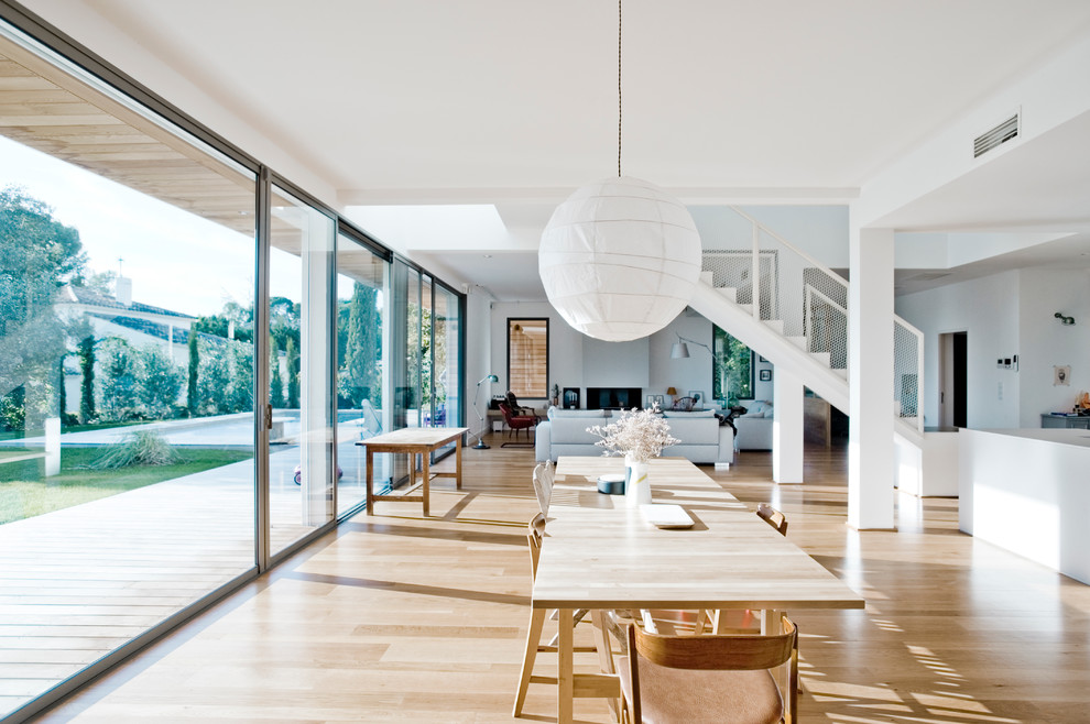Imagen de comedor contemporáneo grande abierto con paredes blancas y suelo de madera clara