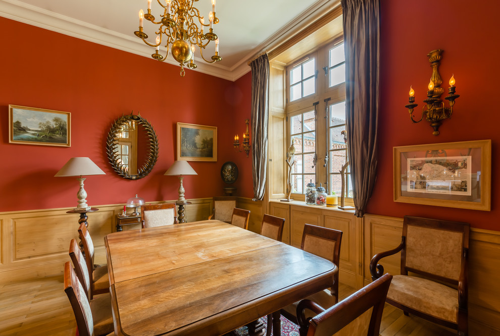 Réalisation d'une salle à manger victorienne avec un mur rouge et un sol en bois brun.