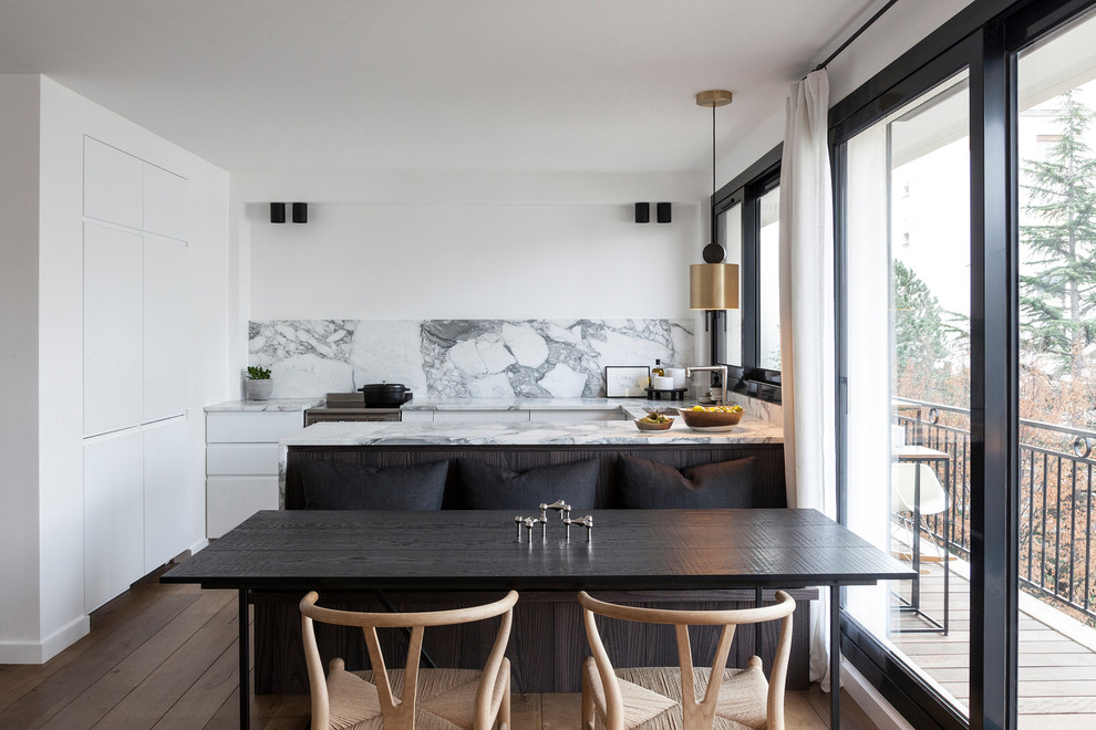 Réalisation d'une salle à manger ouverte sur la cuisine design avec un mur blanc, un sol en bois brun, aucune cheminée et un sol marron.