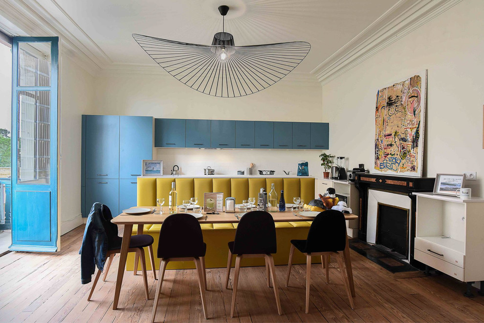 Foto di una sala da pranzo aperta verso la cucina minimal con pareti bianche, pavimento in legno massello medio, camino classico e pavimento marrone