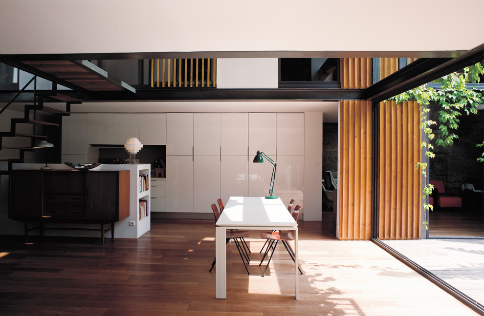 Идея дизайна: гостиная-столовая среднего размера в современном стиле с белыми стенами и паркетным полом среднего тона