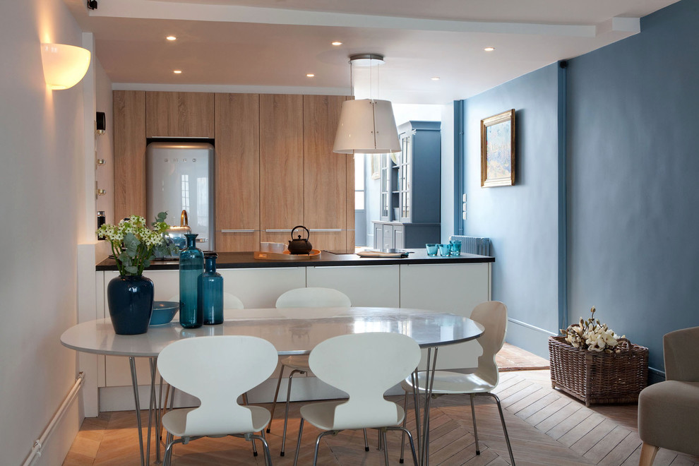 Exemple d'une salle à manger ouverte sur le salon tendance de taille moyenne avec un mur bleu, parquet clair, aucune cheminée et un sol marron.