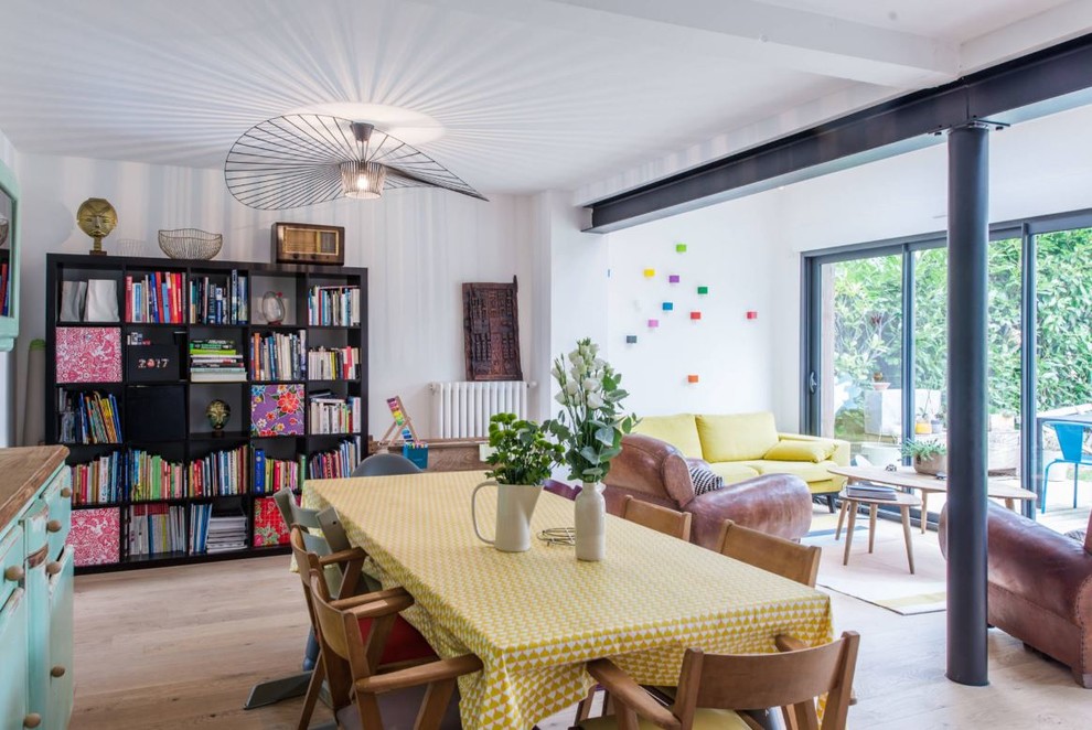 Cette image montre une grande salle à manger ouverte sur le salon design avec un mur blanc, un sol en bois brun et un sol marron.