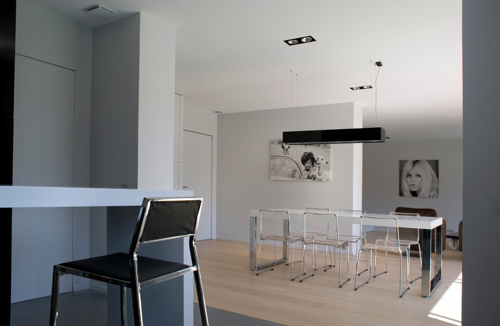 Cette image montre une salle à manger ouverte sur le salon design de taille moyenne avec un mur blanc, parquet clair et aucune cheminée.
