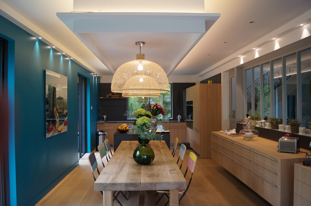 This is an example of a medium sized contemporary kitchen/dining room in Paris with blue walls, light hardwood flooring and no fireplace.