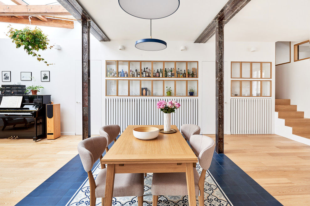 Réalisation d'une grande salle à manger ouverte sur le salon design avec un mur blanc, tomettes au sol, aucune cheminée et un sol bleu.