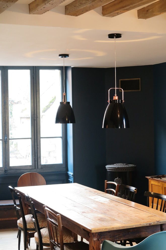 Modelo de comedor campestre abierto con paredes azules, suelo de madera clara y estufa de leña
