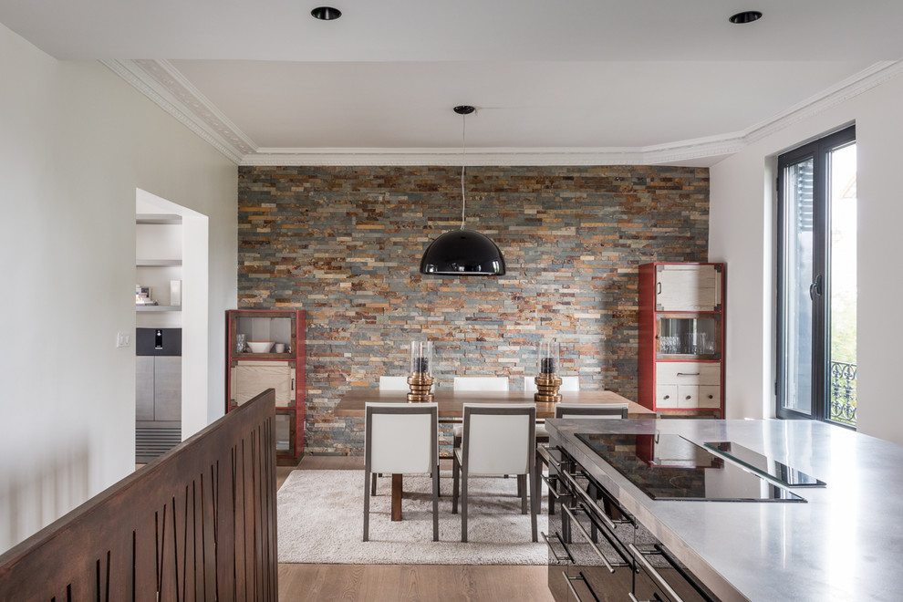 Cette image montre une salle à manger ouverte sur la cuisine design de taille moyenne avec un mur multicolore, un sol en bois brun, aucune cheminée et un sol marron.