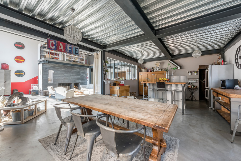 Photo of a large industrial open plan dining room in Lyon with grey walls and concrete flooring.