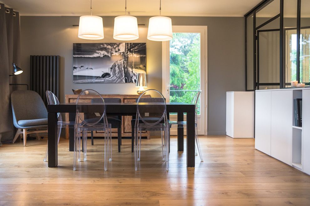 Imagen de comedor actual abierto con paredes grises y suelo de madera en tonos medios