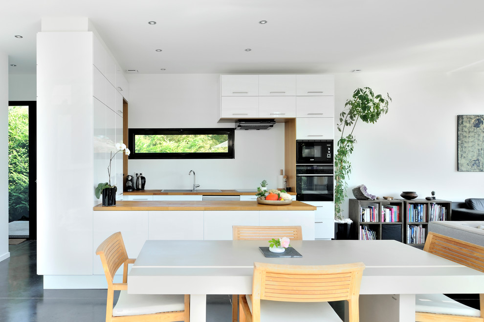 Exempel på ett modernt kök med matplats, med vita väggar och betonggolv