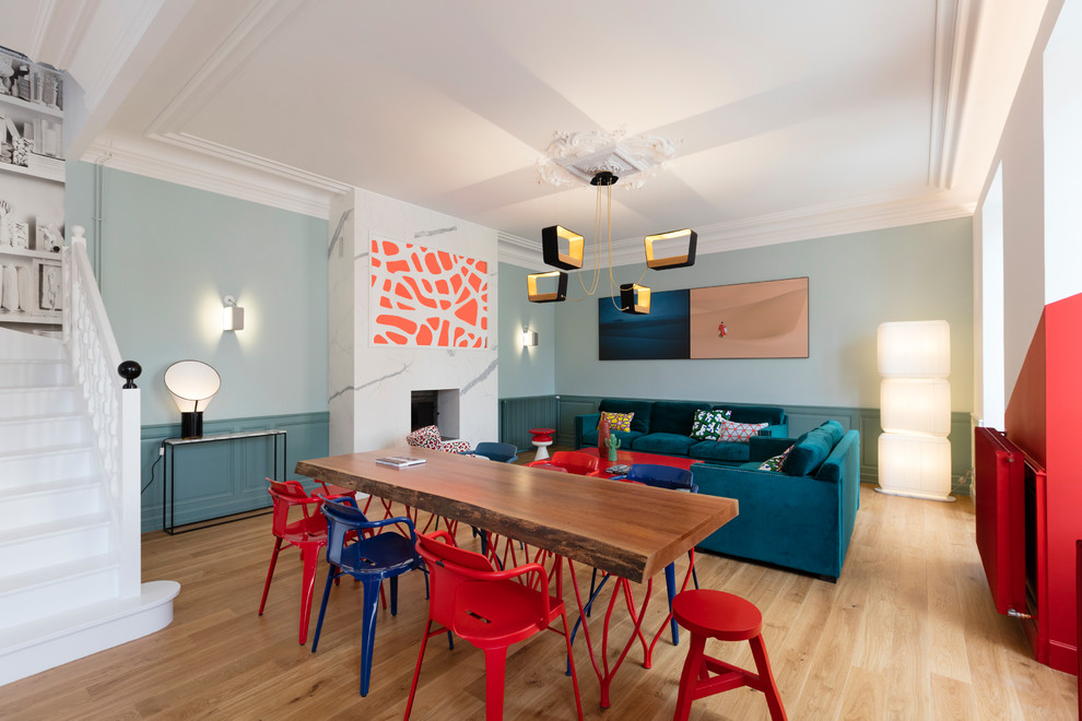 Exemple d'une salle à manger tendance avec un mur bleu, parquet clair et une cheminée standard.