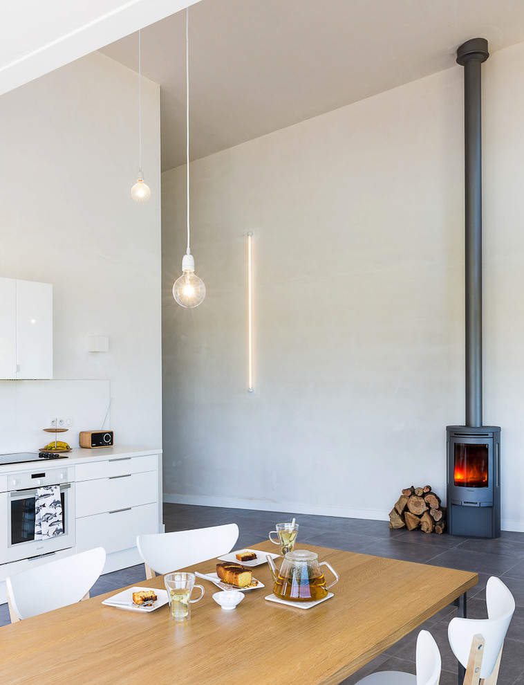 Esempio di una sala da pranzo aperta verso il soggiorno design di medie dimensioni con pareti bianche, stufa a legna e cornice del camino in metallo