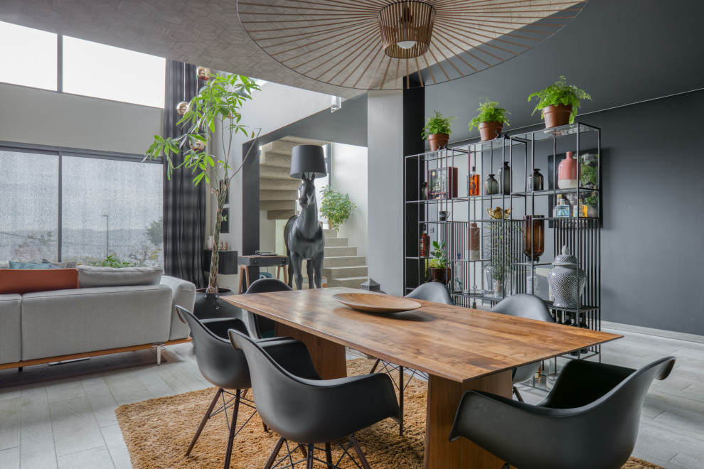 Cette image montre une salle à manger ouverte sur le salon design avec un mur gris et un sol gris.