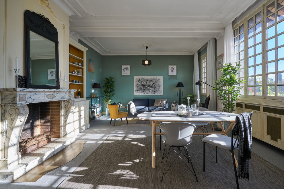 Réalisation d'une salle à manger ouverte sur le salon nordique avec un mur vert, moquette, une cheminée standard, un manteau de cheminée en pierre, un sol gris et éclairage.