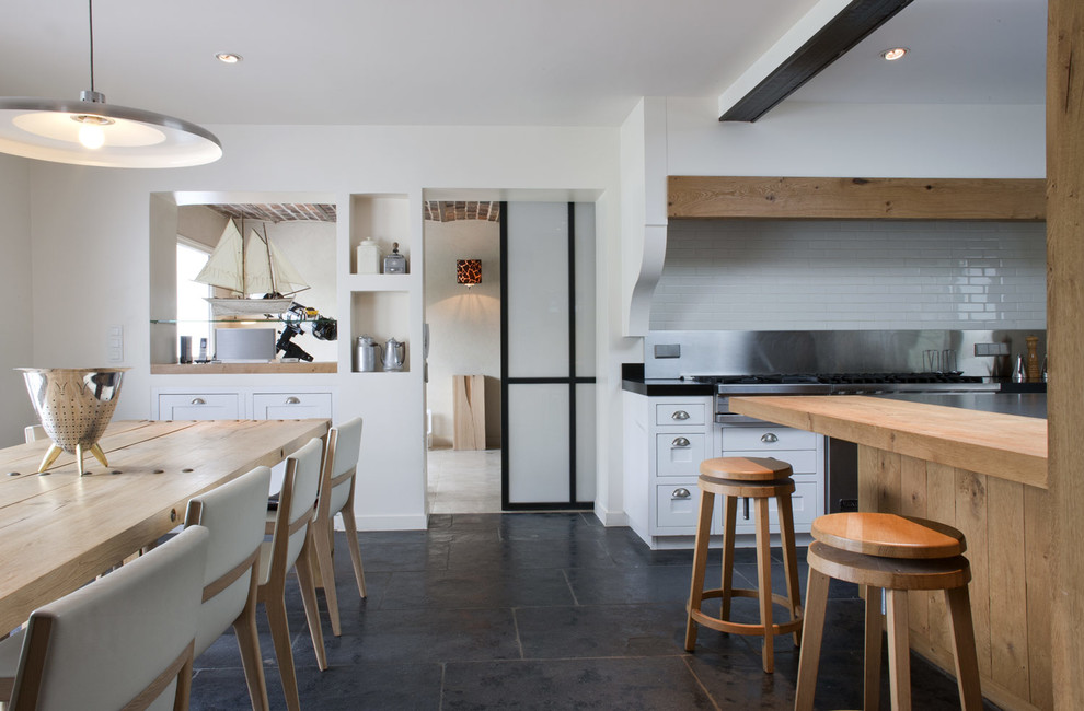 Exemple d'une salle à manger ouverte sur la cuisine montagne avec un mur blanc et un sol noir.