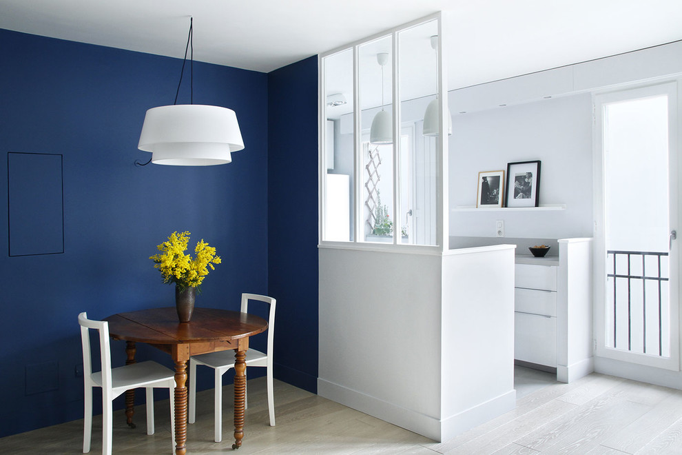 Esempio di una sala da pranzo aperta verso il soggiorno design di medie dimensioni con pareti blu, parquet chiaro e nessun camino
