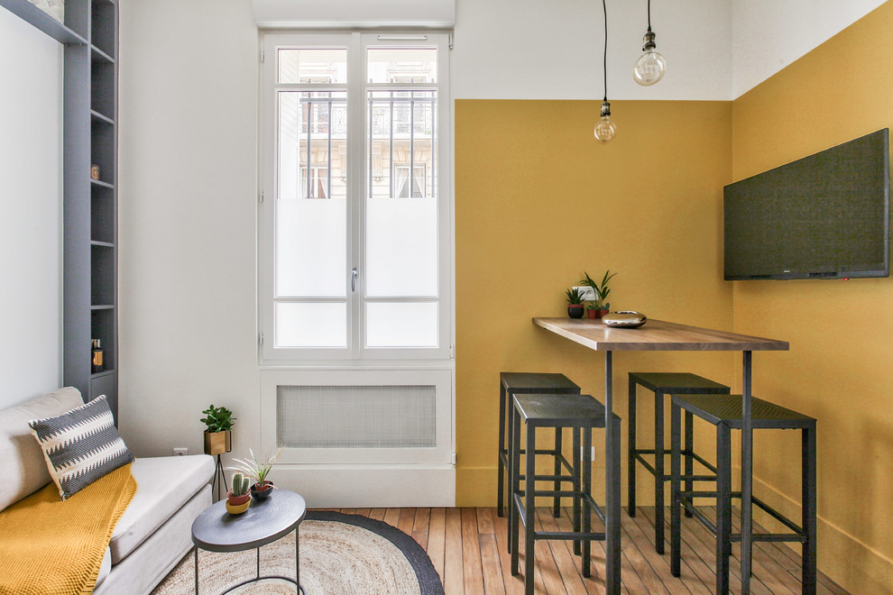 Foto di una sala da pranzo aperta verso il soggiorno industriale di medie dimensioni con pareti gialle, pavimento in legno massello medio, nessun camino e pavimento marrone