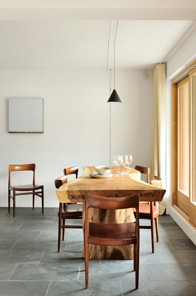 Foto di una sala da pranzo aperta verso la cucina stile rurale con pareti bianche e pavimento nero