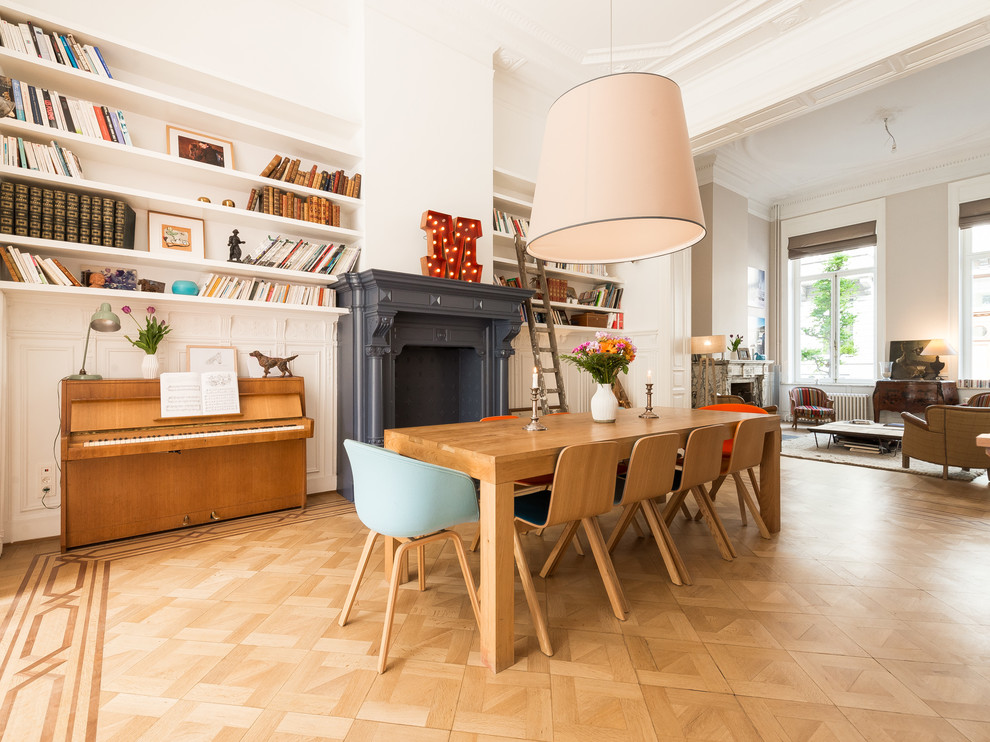 Cette photo montre une salle à manger ouverte sur le salon scandinave avec un mur blanc, un sol en bois brun et une cheminée standard.