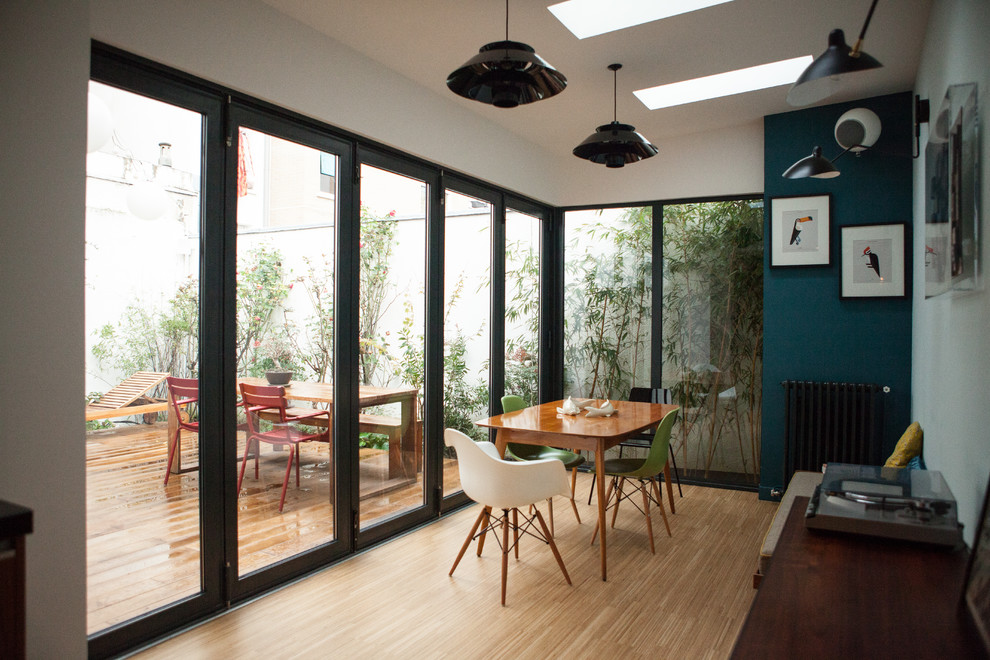 Exempel på en mellanstor modern separat matplats, med ljust trägolv och blå väggar