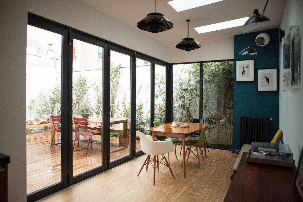 Modelo de comedor contemporáneo de tamaño medio cerrado sin chimenea con suelo de madera clara y paredes azules