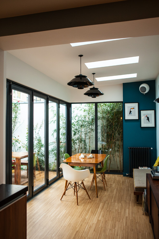 Foto di una sala da pranzo minimal chiusa e di medie dimensioni con pareti blu, parquet chiaro e nessun camino