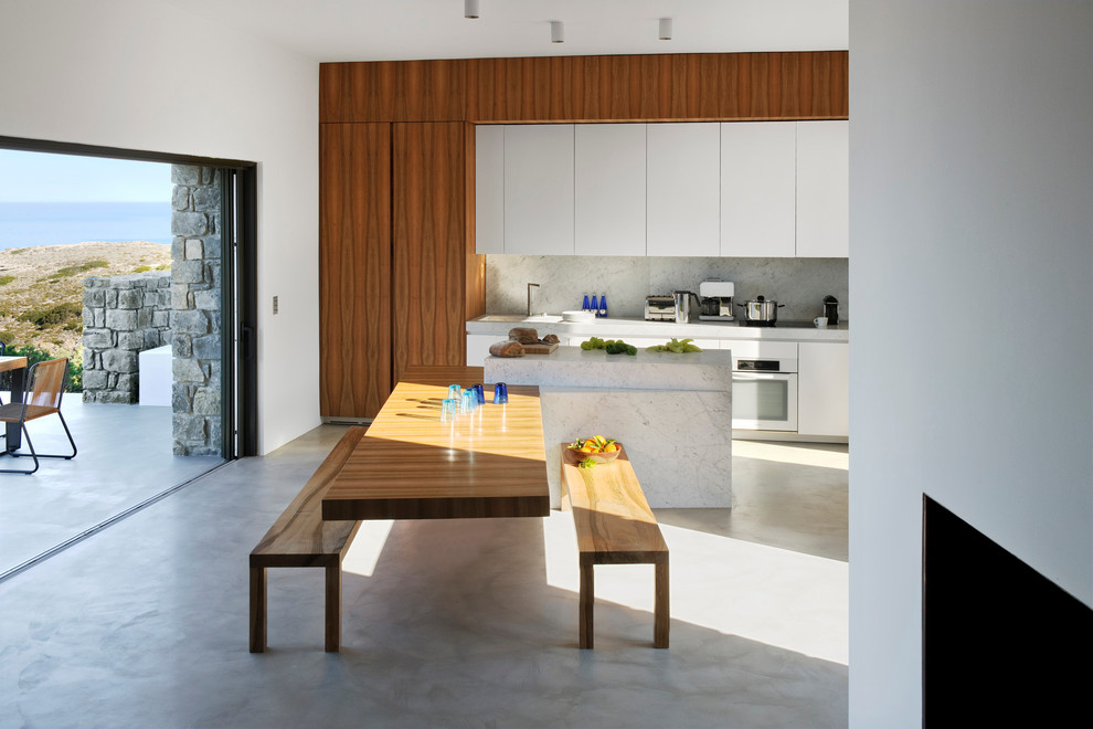 Bild på ett mellanstort funkis kök med matplats, med vita väggar och betonggolv