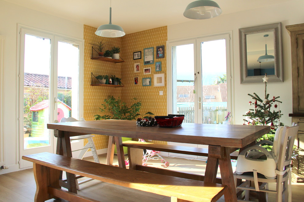 Immagine di una sala da pranzo aperta verso il soggiorno scandinava con pareti gialle, pavimento in laminato e pavimento beige