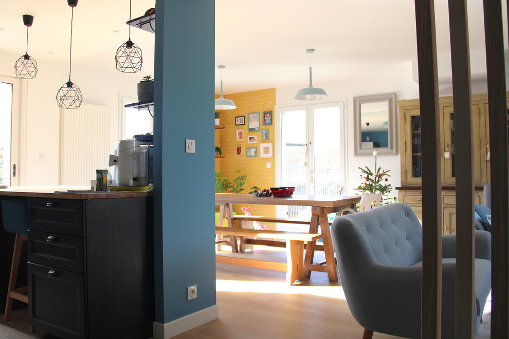 Идея дизайна: гостиная-столовая в скандинавском стиле с желтыми стенами, полом из ламината и бежевым полом