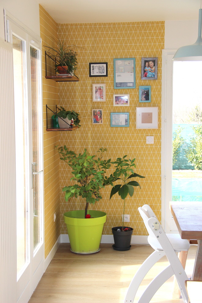 Foto di una sala da pranzo aperta verso il soggiorno scandinava con pareti gialle, pavimento in laminato e pavimento beige