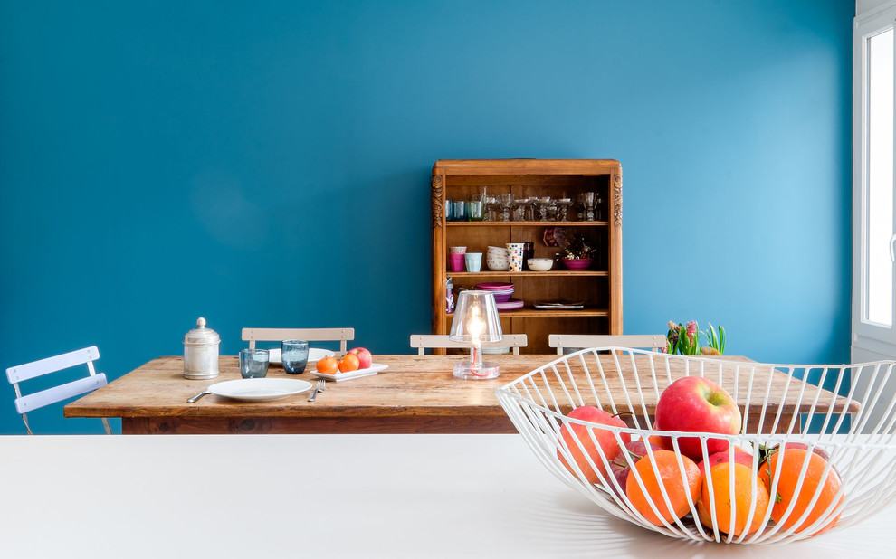 Idee per una sala da pranzo aperta verso il soggiorno minimal con parquet chiaro, pareti blu e stufa a legna