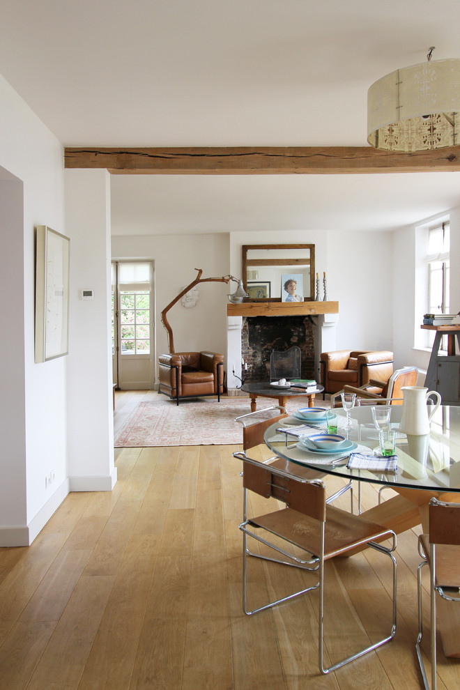 Ispirazione per una sala da pranzo aperta verso il soggiorno minimalista di medie dimensioni con pareti bianche, pavimento in legno massello medio e camino classico