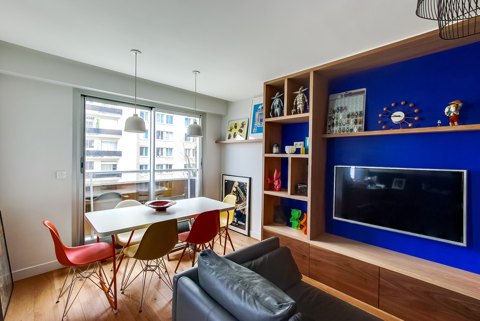 Cette photo montre une petite salle à manger ouverte sur le salon tendance avec un mur bleu, un sol en bois brun et aucune cheminée.