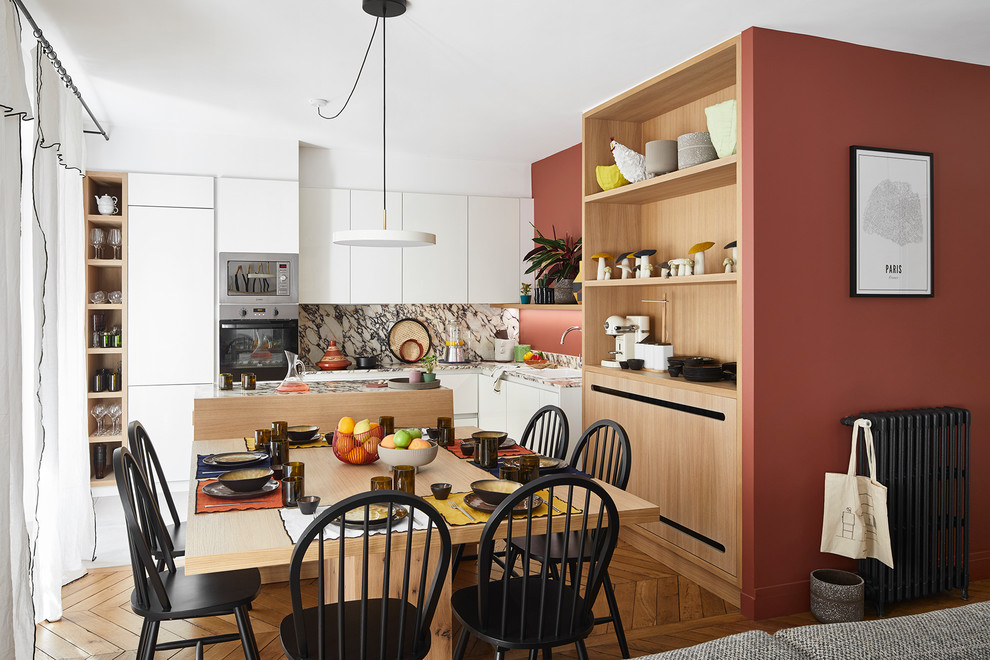 Immagine di una sala da pranzo aperta verso il soggiorno scandinava di medie dimensioni con pareti rosse e parquet chiaro