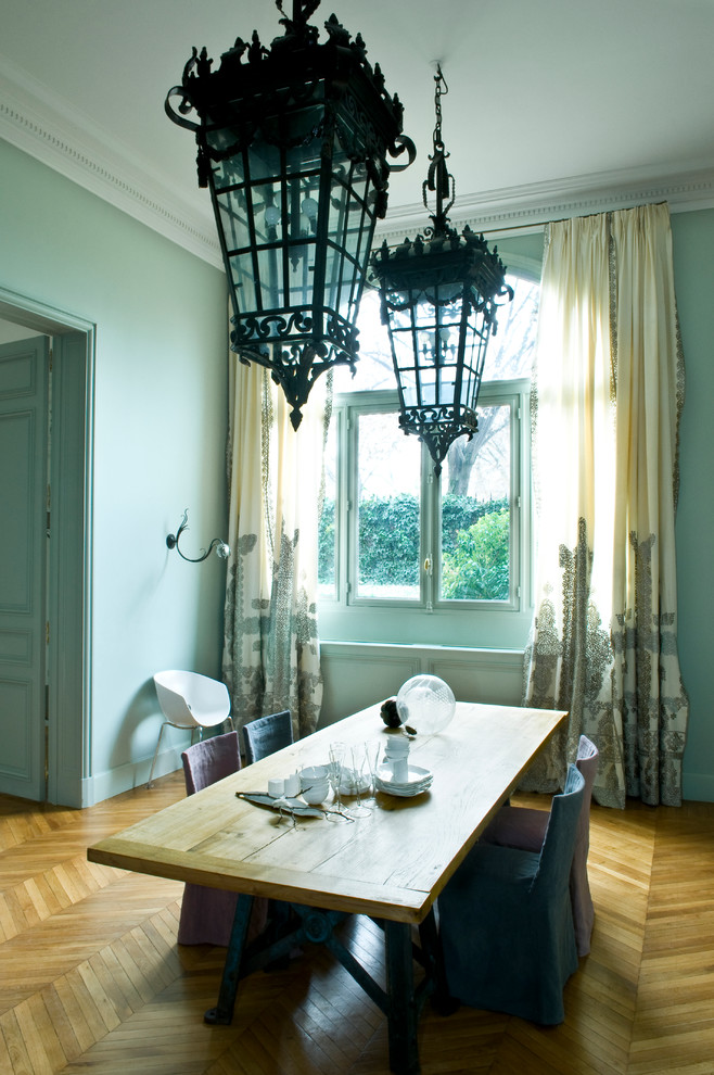 Cette photo montre une salle à manger ouverte sur le salon éclectique de taille moyenne avec un mur bleu, parquet clair, aucune cheminée et un sol beige.