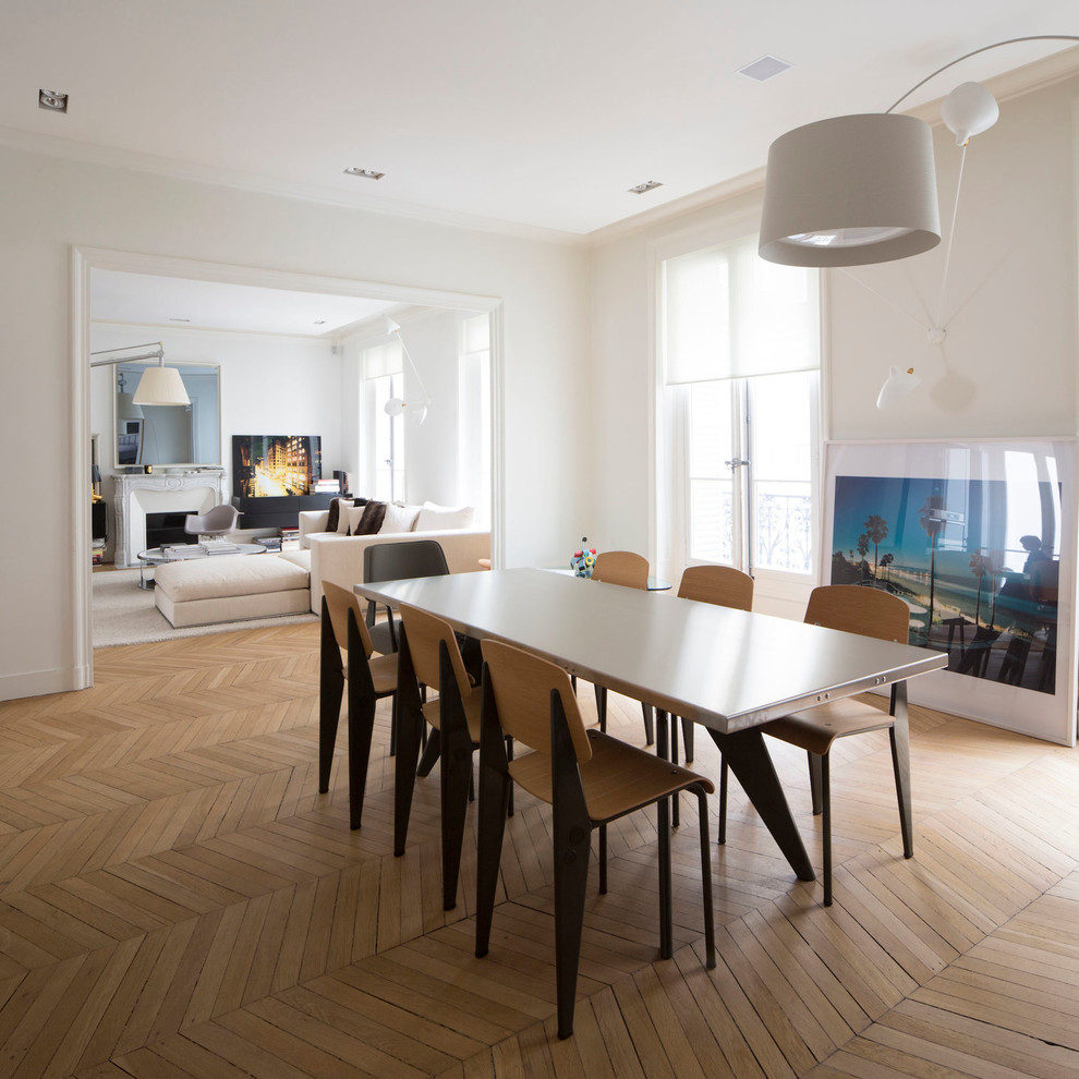 Immagine di una grande sala da pranzo aperta verso il soggiorno contemporanea con pareti bianche, pavimento in legno massello medio e nessun camino