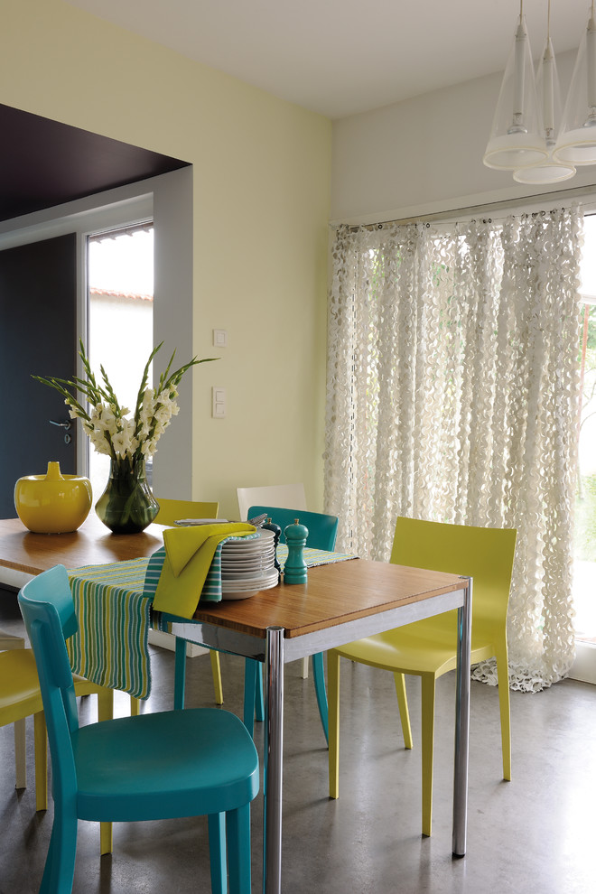 Пример оригинального дизайна: гостиная-столовая среднего размера в современном стиле с желтыми стенами и бетонным полом
