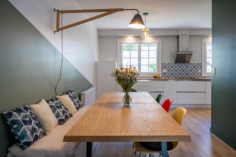 Diseño de comedor de cocina escandinavo grande con paredes verdes, suelo de madera clara y estufa de leña